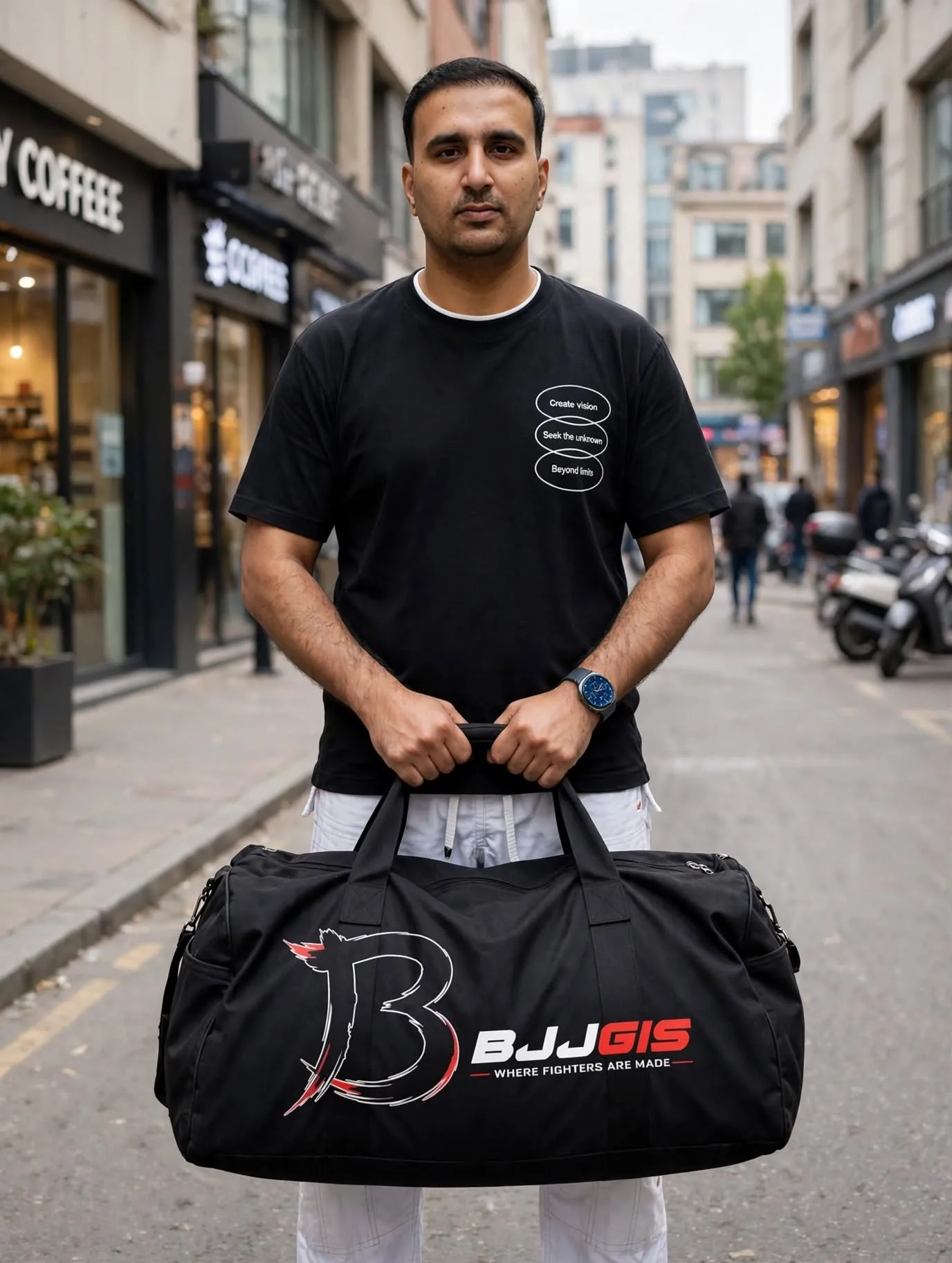 Man holding black BJJGIS duffel Gi bag with large logo in front on city street - BJJ gear bag