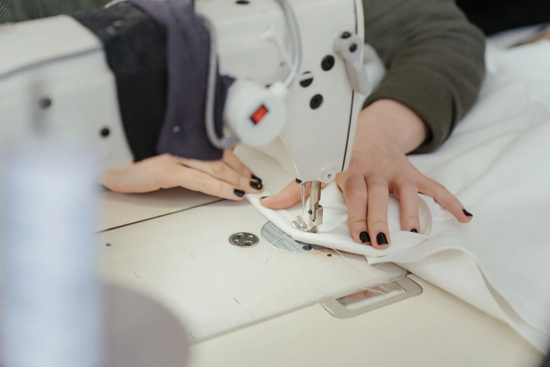 Close-up of hands guiding fabric through a professional sewing machine